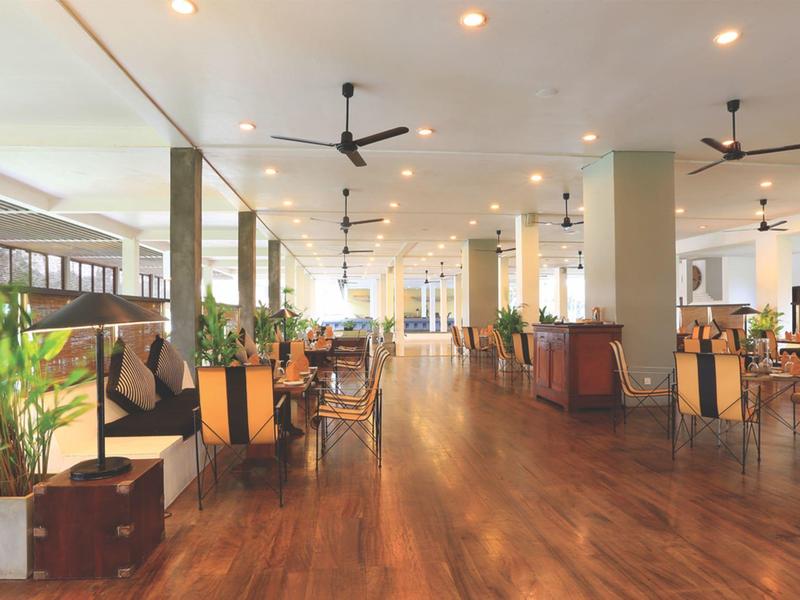 Ruime, lichte eetzaal met houten vloer en moderne plafondventilatoren.