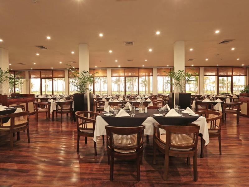 Elegant hotelrestaurant met houten vloer, gedekte tafels en stoelen in warm licht.