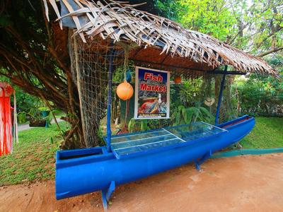 Blaue Bootskühlvitrine mit Dach aus Palmenblättern in einem grünen Garten