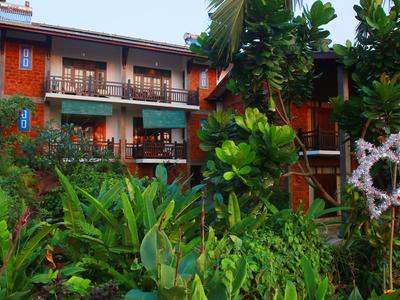 Mehrstöckiges Holzhaus in grünem Garten mit üppigen Pflanzen und Stern-Dekoration aus Ästen.
