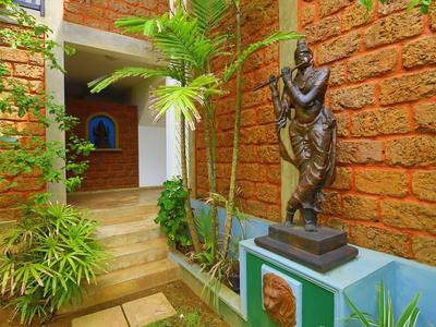 Innenhof mit rotem Steinmauer, grünen Pflanzen und einer bronzenen Statue auf blauem Sockel.