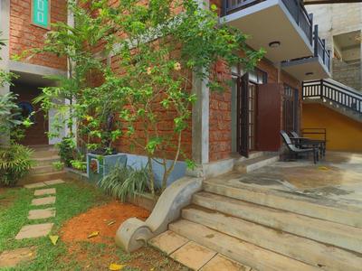 Haus mit roter Ziegelwand, Treppe, Pflasterweg und grünem Garten mit Bäumen und Pflanzen.