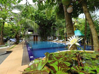 Ein ruhiger Poolbereich mit Liegestühlen und üppiger grüner Bepflanzung in einem tropischen Hotelgarten.