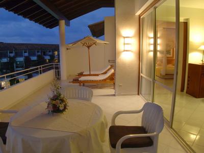 Lit balcony with table, chairs, and lounge chairs at dusk in a hotel.