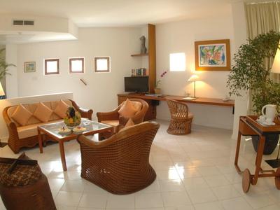 Cozy living area with wicker furniture, carpet, and lighting in a bright room.