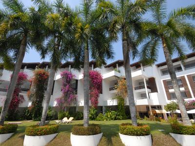 Hotel building with white walls surrounded by tall palm trees and colorful flowers