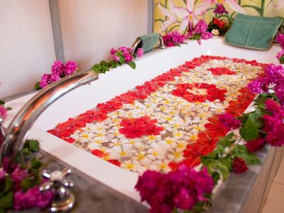Relaxing spa with flower-decorated bathtub and rose petals