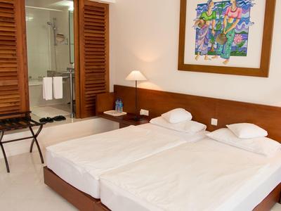 Brightly furnished double room with two single beds and view of the bathroom.