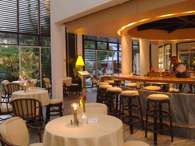 Bright restaurant with round tables, chairs, and a bar with stools.