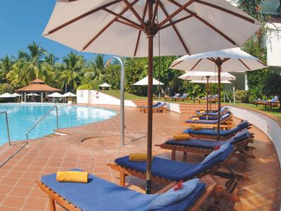 Pool area with blue loungers and white umbrellas under sunny weather