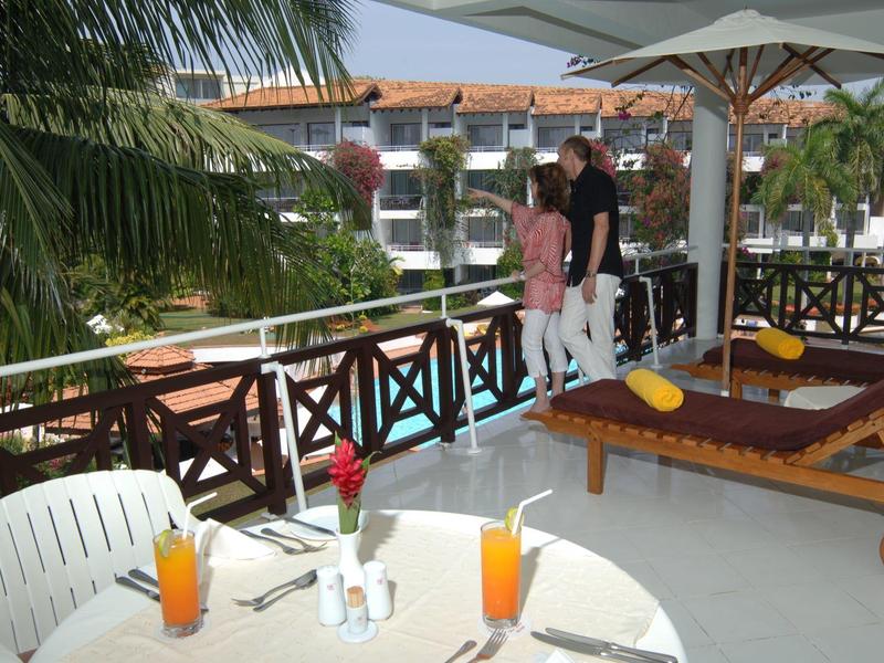 View of a terrace with lounge chairs, a table with drinks, and tropical plants.