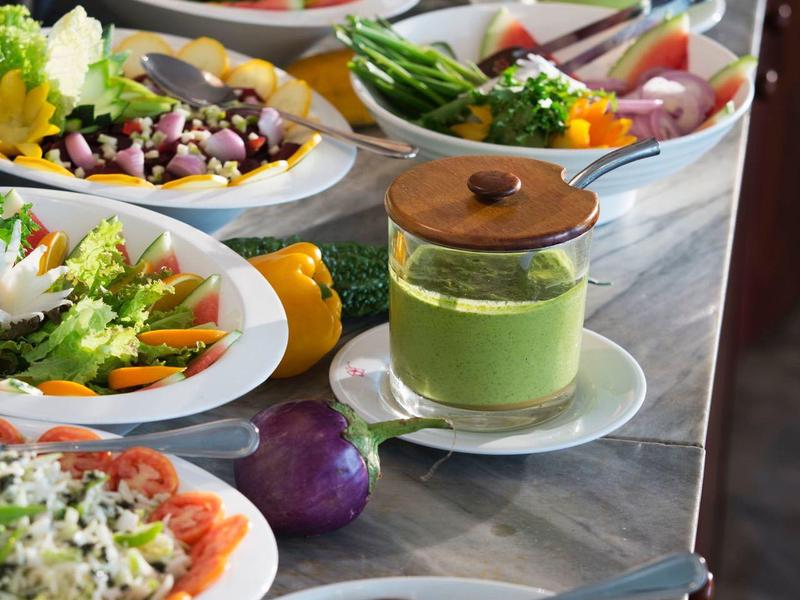 Varied buffet with fresh salad, vegetables, and dressings in a hotel setting.