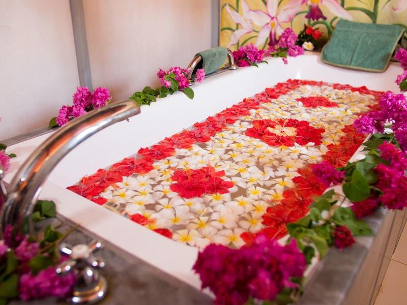 Relaxing spa with flower-decorated bathtub and rose petals