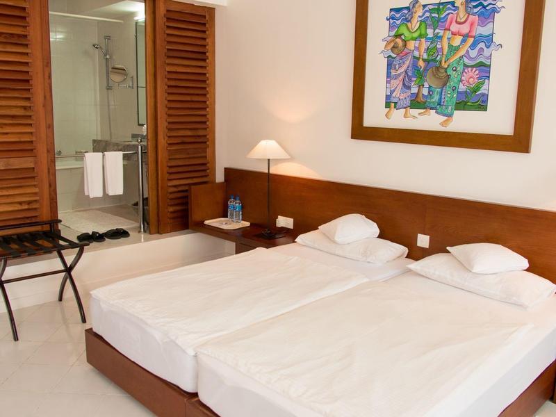 Brightly furnished double room with two single beds and view of the bathroom.