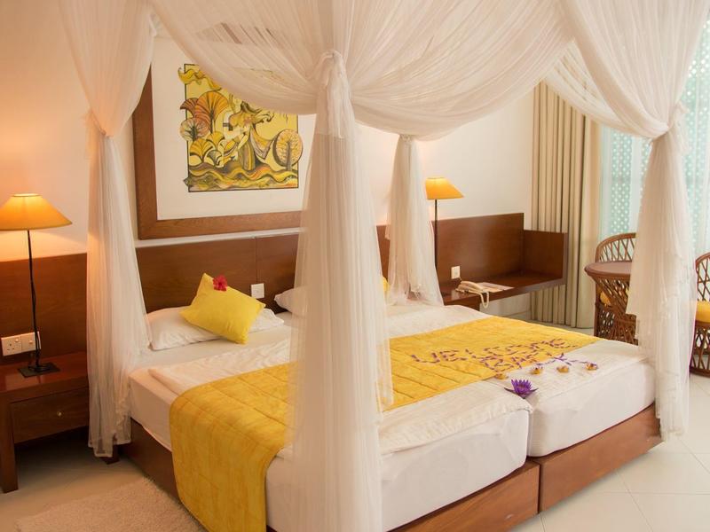 Bright hotel room with two single beds, canopy, and yellow bedding