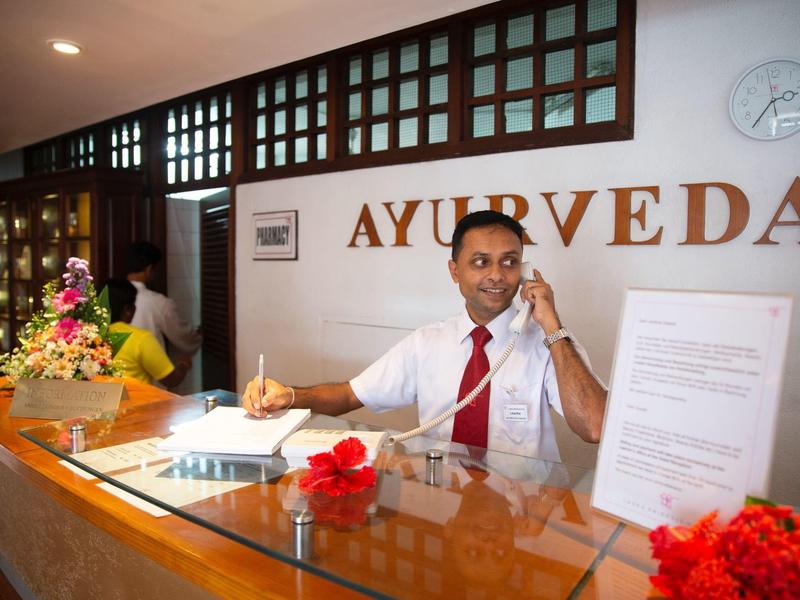 Hotel reception with staff member using phone and taking notes to assist guests.