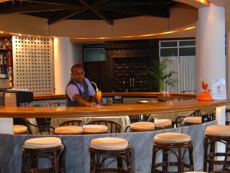 Bar area with wooden stools and a bartender in a cozy restaurant.