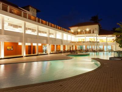 Modernes Hotel mit beleuchtetem Swimmingpool bei Nacht und klarer Architektur.