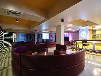 Moderní hotelová lounge s kulatými nízkými pohovkami a osvětleným barem