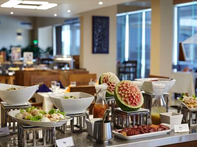 Ein Buffet mit Früchten, Salaten und warmen Speisen in einem hellen Restaurant.