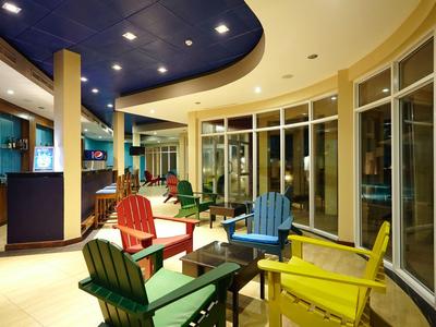 Barevné židle kolem stolu v moderním, světlém interiéru s velkými okny.