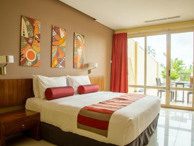 Moderní hotelový pokoj s velkou postelí, červenou výzdobou a přístupem na balkon.