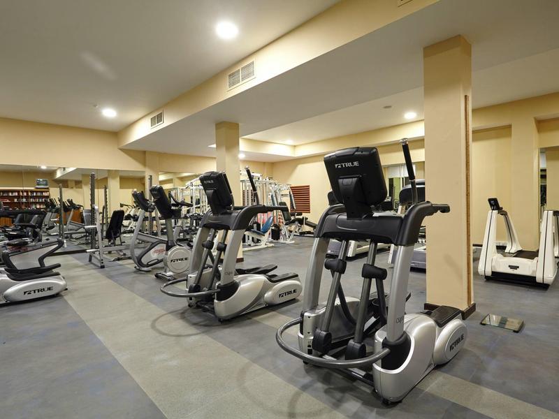 Moderní fitness místnost s tréninkovým vybavením v hotelu.