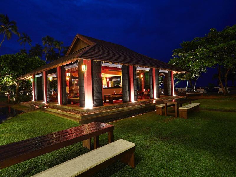 Osvětlený rekreační dům s velkou zahradou a lavicemi v noci.