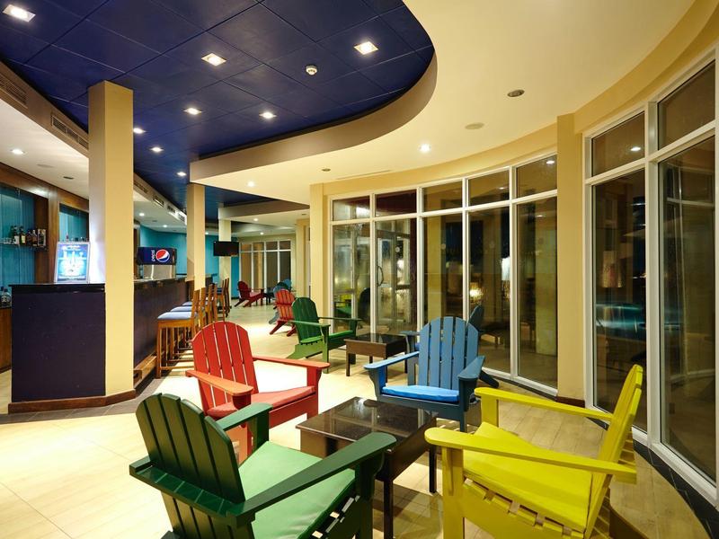 Barevné židle kolem stolu v moderním, světlém interiéru s velkými okny.