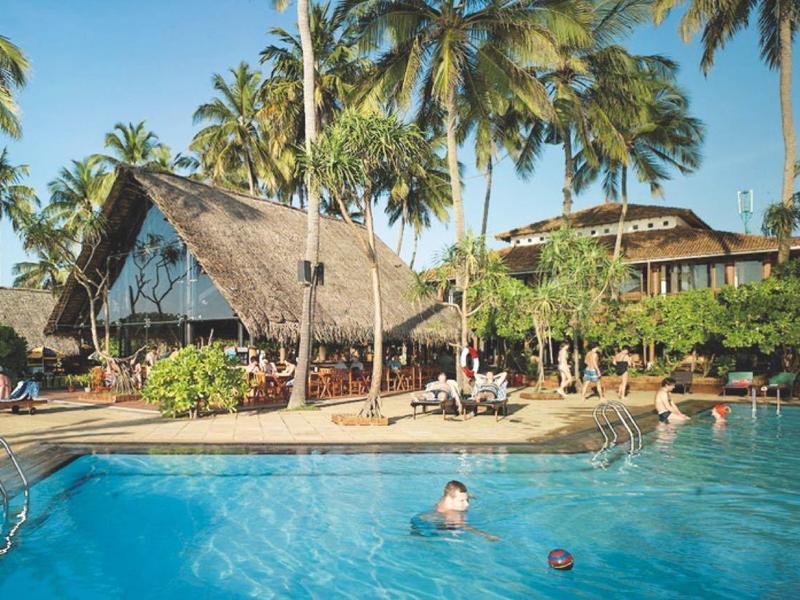 Groot buitenzwembad voor tropische villa's met palmbomen en een heldere lucht.