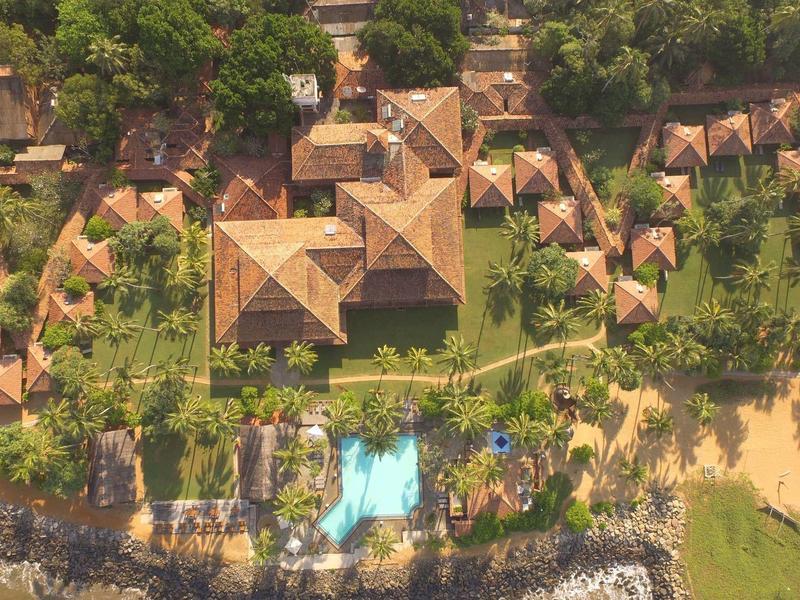 Luchtfoto van een resort met meerdere kleine hutten, centraal gebouw en zwembad aan het water