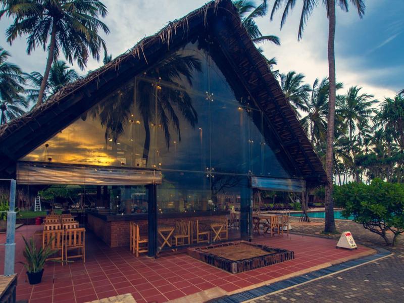 Gezellig tropisch restaurant met rieten dak en lantaarns bij zonsondergang.