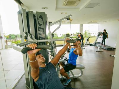 Dos hombres hacen ejercicio en máquinas de gimnasio en un gimnasio moderno y luminoso de hotel.