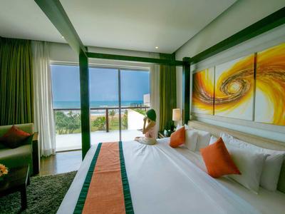 Habitación de hotel moderna con cama grande, vista al mar y decoración artística naranja sobre el cabecero.