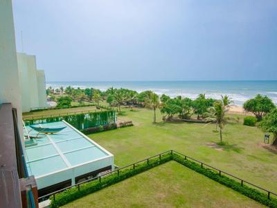 Vista de jardín cuidado y playa bajo cielo despejado junto a edificio del hotel.