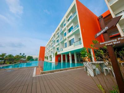 Hotel moderno con piscina, terraza y agua turquesa bajo un cielo azul.