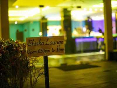 Cartel de Shisha Lounge frente a un edificio iluminado por la noche.