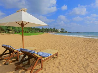 Due sedie a sdraio con ombrellone su una spiaggia di sabbia deserta vicino al mare.