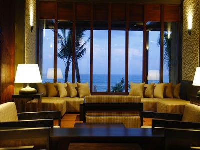 Accogliente lounge con divani, poltrone e tavolo con vista sul mare e palme.