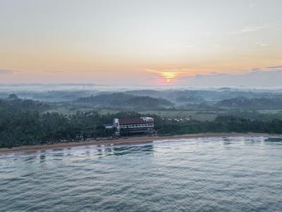 Alba su una costa con un hotel sulla spiaggia e dolci colline sullo sfondo.