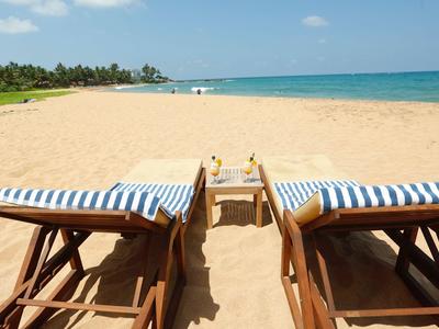 Due sdraio a strisce blu e bianche su una spiaggia sabbiosa soleggiata con vista sul mare.