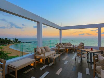 Terrazza aperta con comodi posti a sedere e vista sulla spiaggia al tramonto.