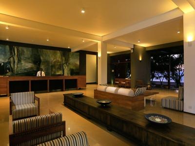 Area comune arredata modernamente con posti a sedere e grande tavolo con illuminazione serale.