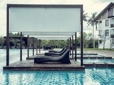 Zwembad met ligstoelen en zonnescherm in een hotelresort.