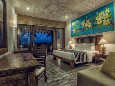 Gezellige hotelkamer met houten ontwerp, bed, tafel, bank en grote bloemenschildering aan de muur 's nachts.