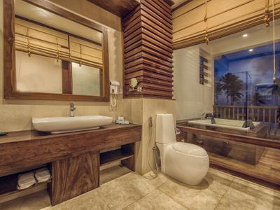 Moderne badkamer met houten accenten, dubbele wastafels, toilet en groot bad met glazen wand.