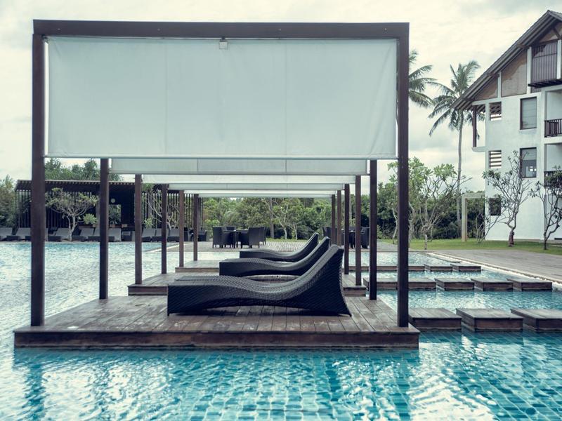 Zwembad met ligstoelen en zonnescherm in een hotelresort.