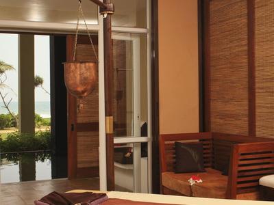 Gemütlicher Massageraum mit Holzmöbeln und offenem Blick auf Garten mit Pool.