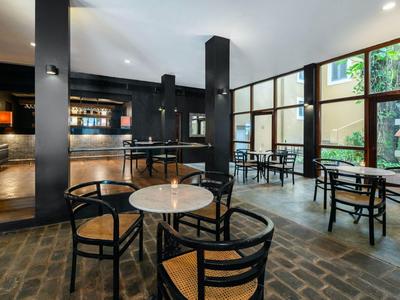 Moderner Caféinnenraum mit schwarzen Möbeln, Marmortischen und großen Fenstern, helles Tageslicht.