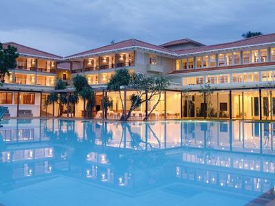 Großes Hotel mit beleuchtetem Außenpool und mehrstöckigem Gebäude bei Dämmerung.